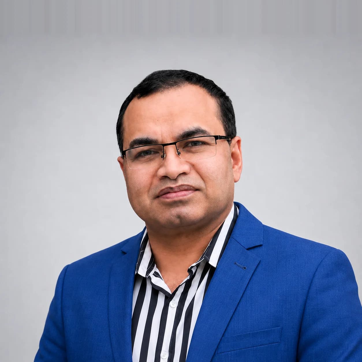 Professional portrait of Jewel Khan, Chairman & CEO, wearing a blue blazer and striped shirt.